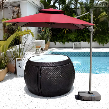 A poolside scene showcases the Midnight Riviera Collection from Landmark Decor, with a round rattan table and glass top for alfresco dining under a red umbrella. Surrounded by potted green plants and adjacent to a blue-tiled pool, the setting uses weather-resistant materials for lasting enjoyment.