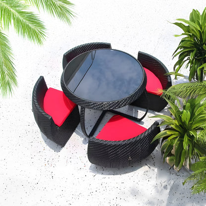 The Midnight Riviera Collection by Landmark Decor features a circular glass-top table and four black wicker chairs with red cushions, perfect for alfresco dining on a speckled white surface. Palm leaves frame the scene, adding tropical charm to your outdoor space.