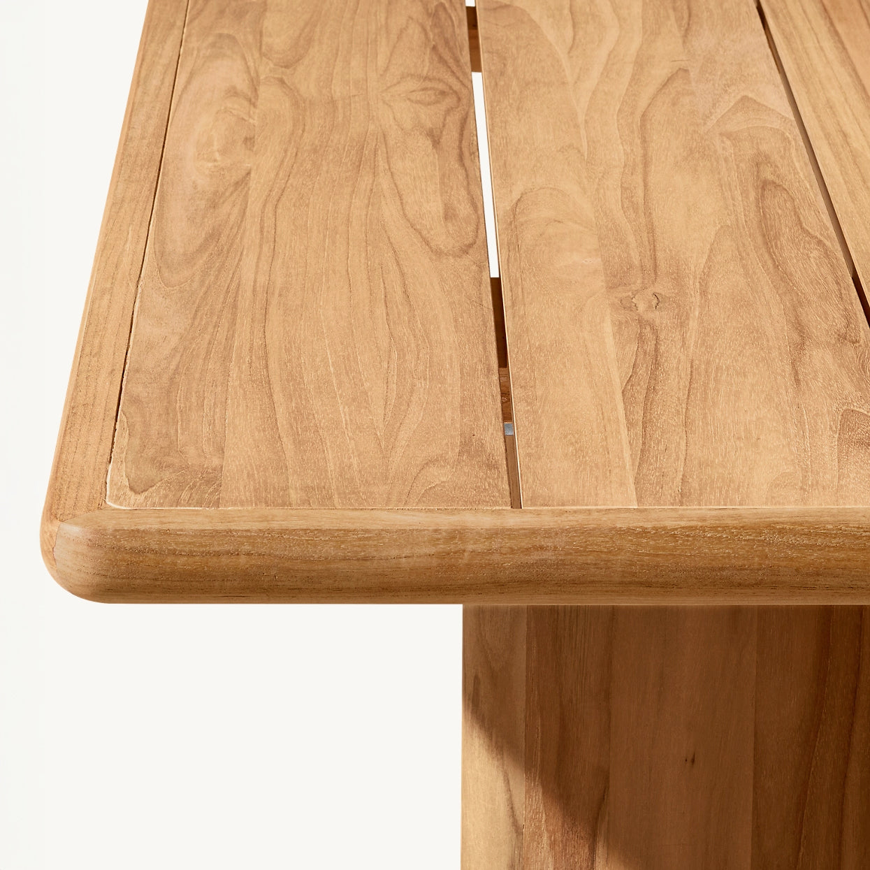 A close-up of The Hidden Canyon Collection table corner by Landmark Decor reveals detailed wood grain, ideal for alfresco dining. Crafted from weather-resistant materials, it features a smooth, light-finished surface with a unique design slot against a neutral background.