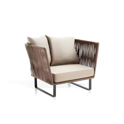 The Sierra Luxe Collection by Landmark Decor is a modern armchair featuring a sleek design with woven back and side panels, weather-resistant light-colored cushions, and thin metal legs. Its white background enhances its contemporary style and outdoor-friendly appeal.