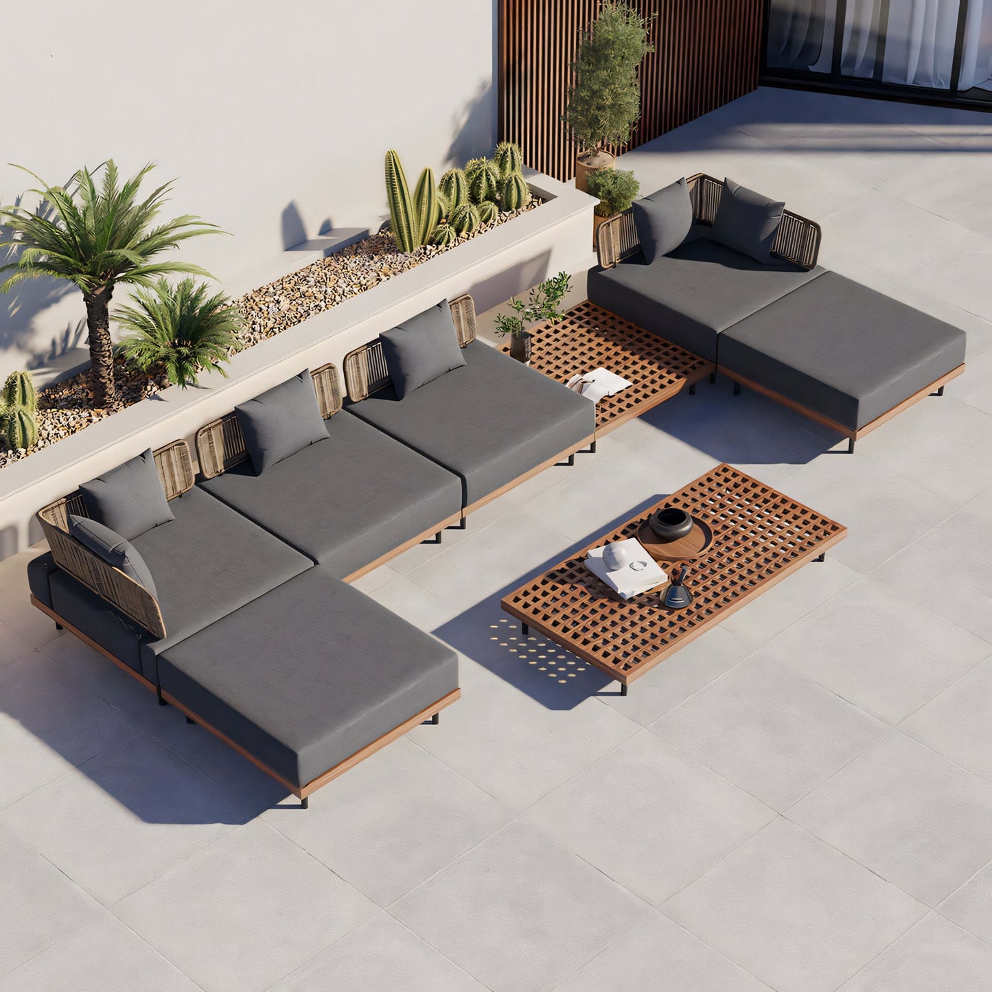 The Oceanview Oasis Collection by Landmark Decor showcases a modular gray outdoor sofa with all-weather frames and weather-resistant cushions, paired with a wooden coffee table adorned with small decor items. Cacti and tall plants against a white stucco wall complete the modern, minimalist patio setting.