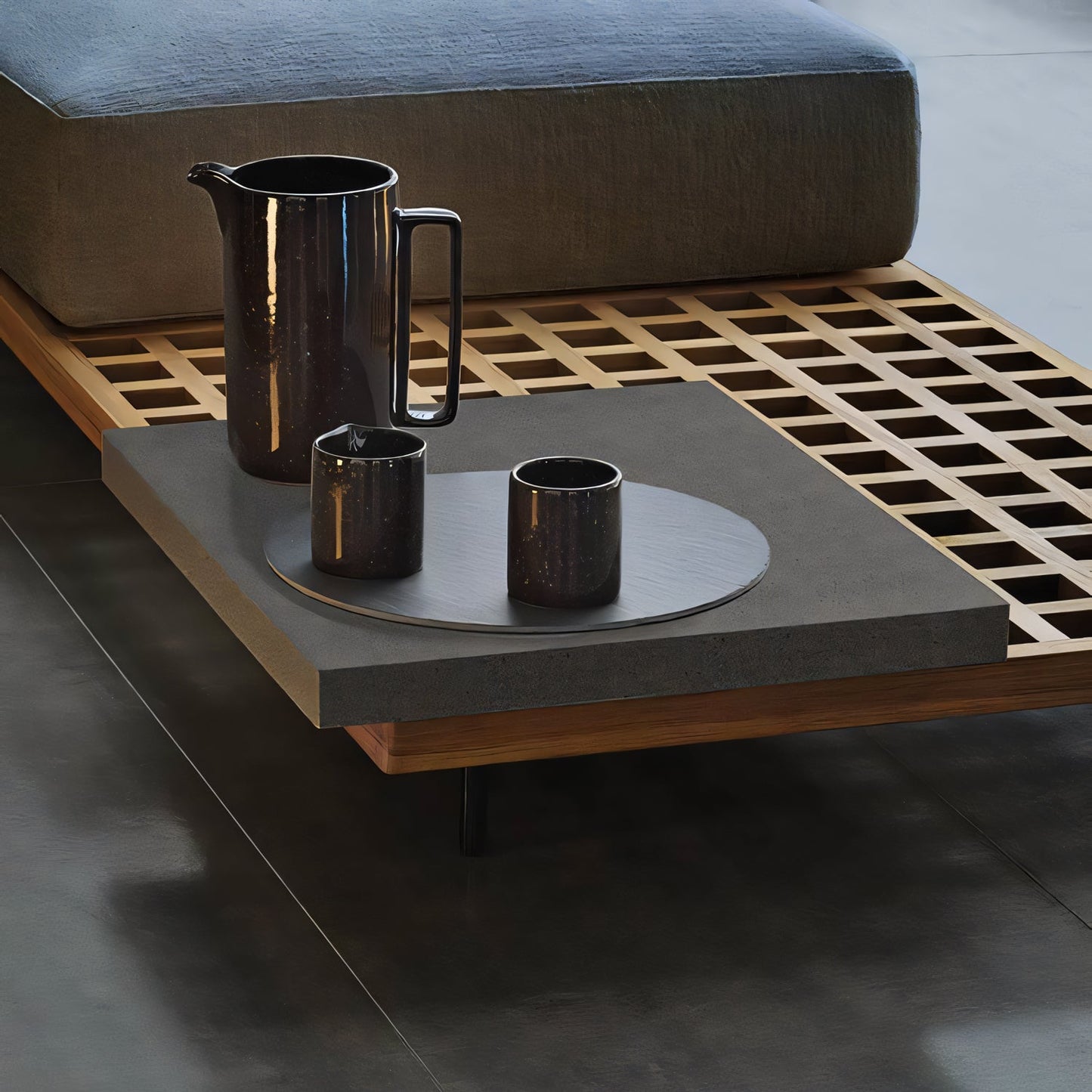 The Oceanview Oasis Collection by Landmark Decor includes a modern coffee table adorned with a dark ceramic pitcher and two cups on a round tray atop a wooden grid platform, paired with outdoor sofas. This minimalist design features muted colors and sleek lines, perfect for spaces with all-weather frames and weather-resistant cushions.