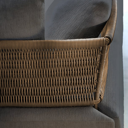 Close-up of a chair from Landmark Decors Oceanview Oasis Collection, featuring a woven rattan backrest with a warm brown hue and a textured gray fabric seat. The design blends natural elements with contemporary style, perfectly complementing outdoor sofas with weather-resistant cushions.