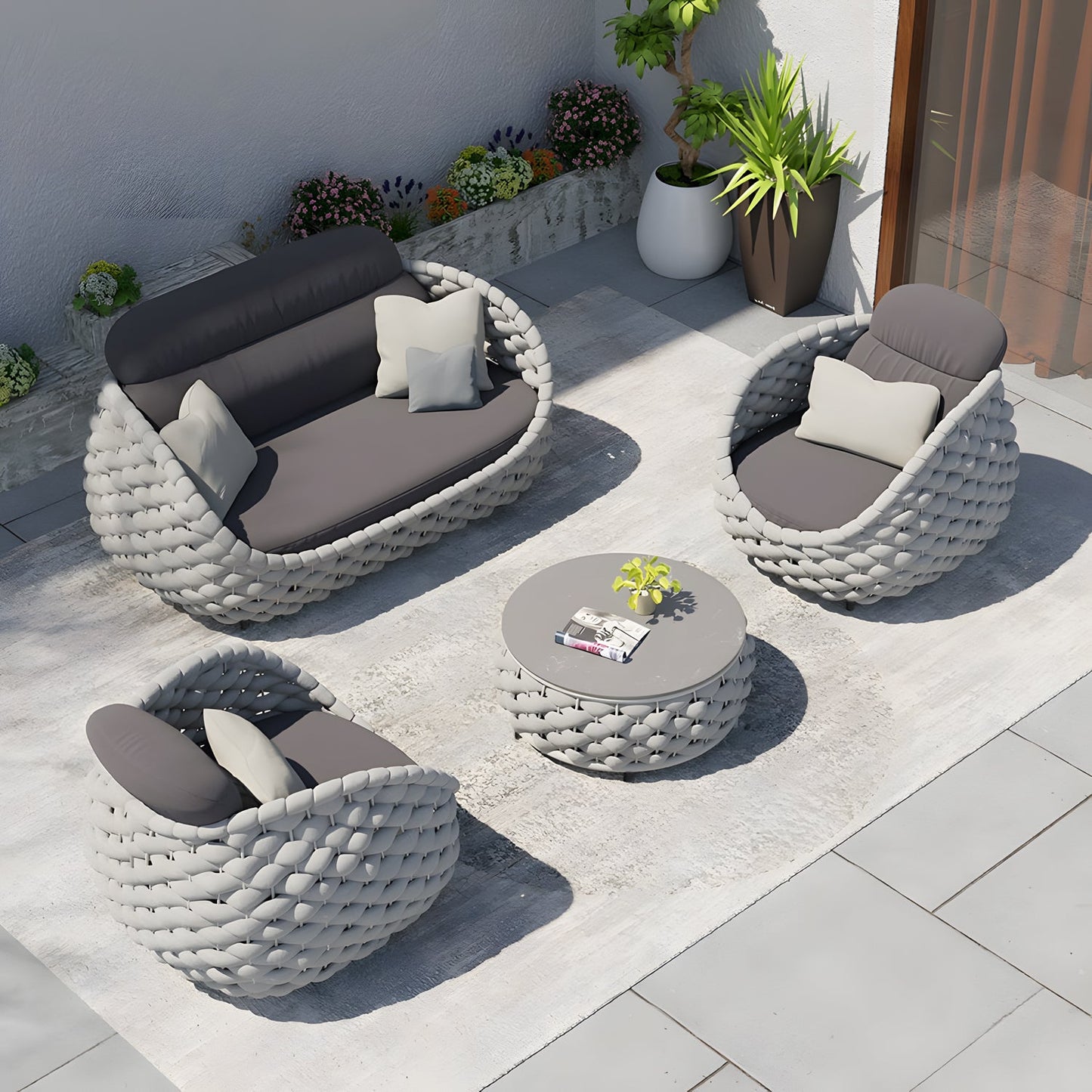The Nordic Lux Collection by Landmark Decor features a modern outdoor patio set with a gray woven loveseat, two armchairs with weather-resistant cushions, and a round coffee table. The setup includes a potted plant and small wall plants, all on a sunlit gray patterned rug.