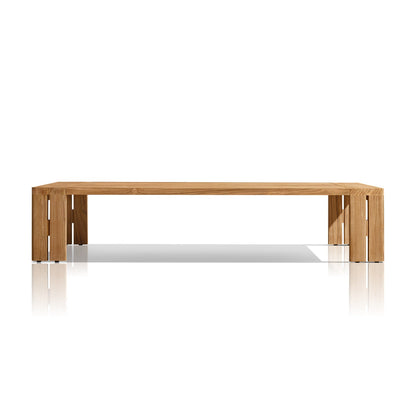 The Golden Horizon Collection by Landmark Decor features a minimalist wooden table with a rectangular top, thick angled legs, and a warm natural wood finish. It complements outdoor sofas with weather-resistant cushions while casting shadows on a reflective white surface.