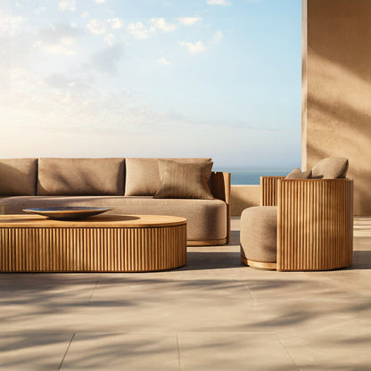 Landmark Decors Coastal Harmony collection creates a serene and stylish outdoor space with a brown wicker sofa and armchair featuring weather-resistant cushions. A round wicker coffee table with a dark bowl completes the look, all set against an ocean view under a blue sky.