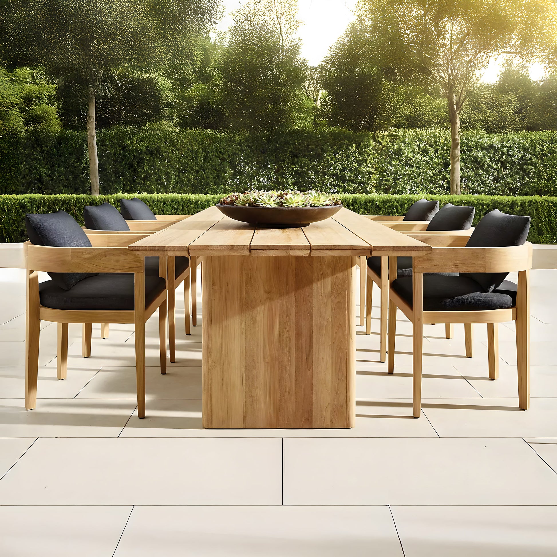 The Summer Solstice Collection by Landmark Decor offers an outdoor patio set perfect for alfresco dining, featuring a long wooden table and eight chairs with black cushions, all made from weather-resistant materials. It complements light-colored tiles amidst lush greenery under a sunny sky.