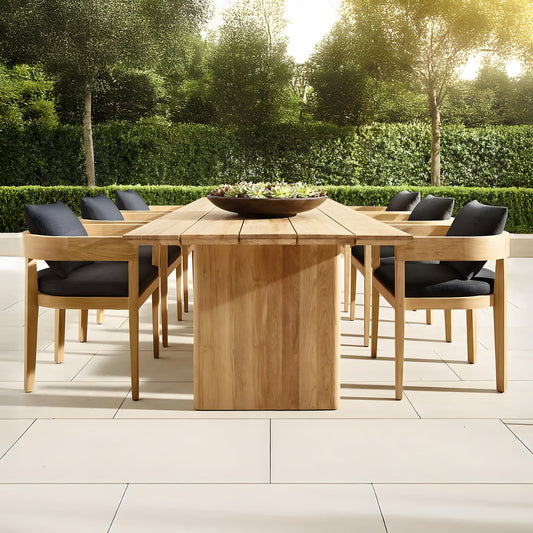 The Summer Solstice Collection by Landmark Decor offers an outdoor patio set perfect for alfresco dining, featuring a long wooden table and eight chairs with black cushions, all made from weather-resistant materials. It complements light-colored tiles amidst lush greenery under a sunny sky.