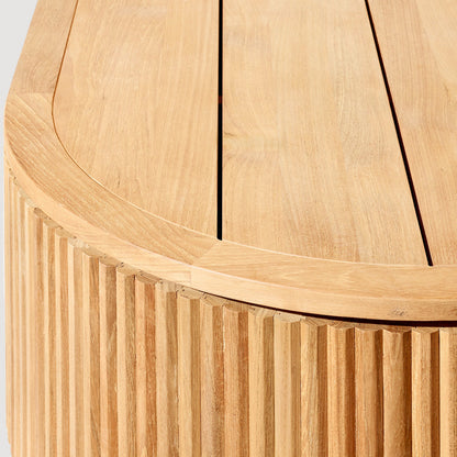 Close-up of the Landmark Decor Coastal Harmony table in light wood with a smooth, rounded edge and vertical slats. Visible grain patterns on its warm-toned surface create an inviting contrast against a white background, complementing luxurious outdoor sofas for an appealing patio setup.