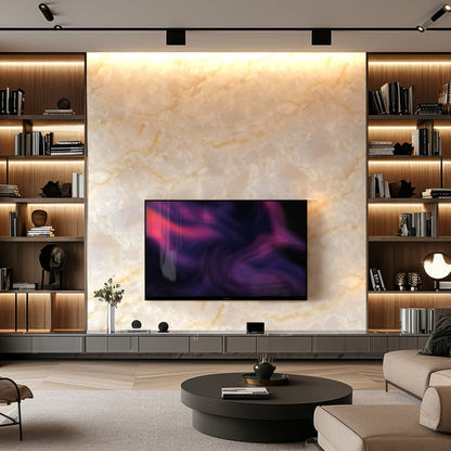 A modern living room features a large marble accent wall with Landmark Decor’s Luxe Shine Marble Durable PVC Wall panels, a mounted TV, built-in shelving, elegant decor accents, and a round coffee table in front.