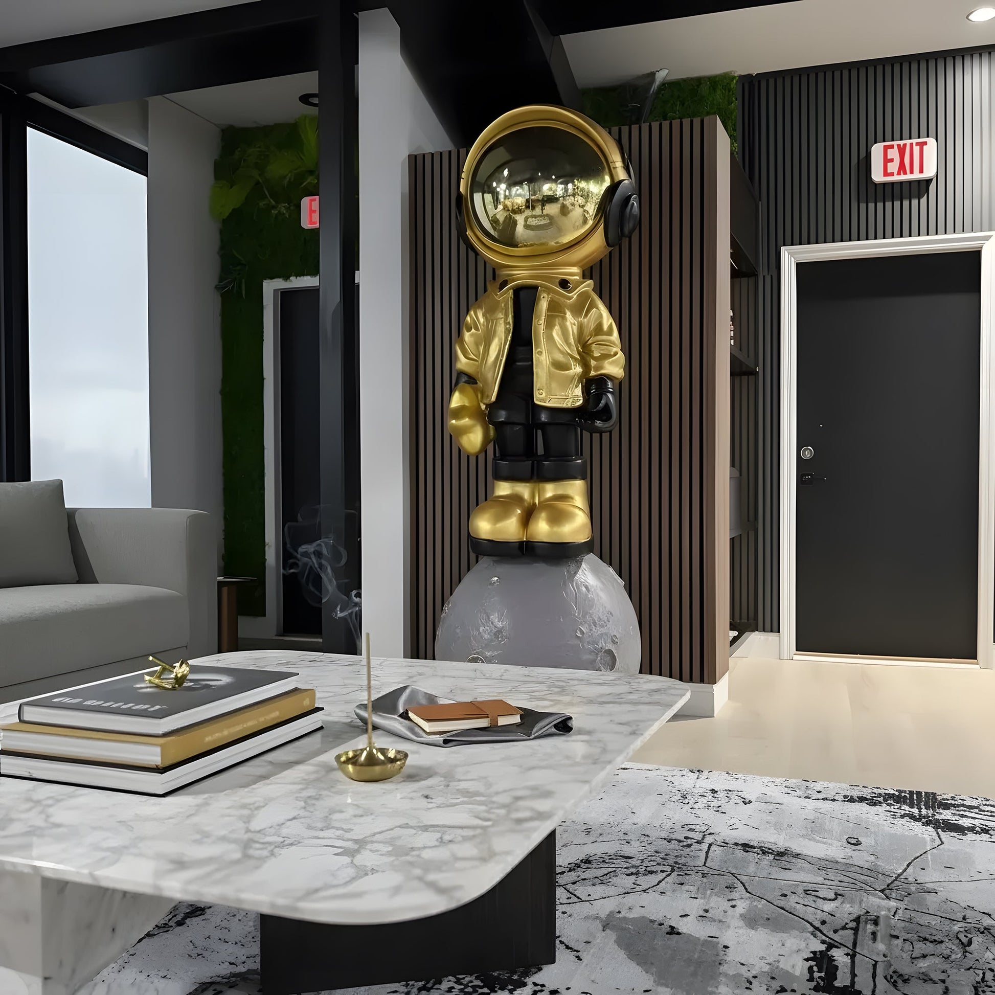 The "Astronaut of the Stars" by Landmark Decor is a gold and black astronaut statue on a moon-like base, adding artistic flair to modern spaces with marble coffee tables and books.