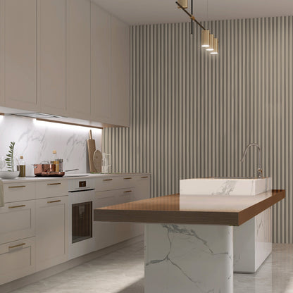Modern kitchen with white cabinets, marble countertops, wood-trimmed island, built-in oven, and a Landmark Decor Light Gray WPC Fluted Slat Wall Panel creating a vertical accent beneath stylish pendant lighting.
